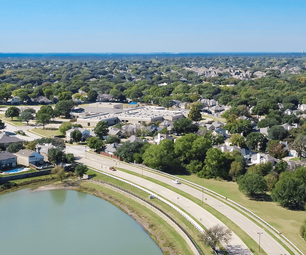 Aerial view residential neighborhood with Grapevine Lake in horizontal line. Row of upscale two story suburban residential houses near local pond in Flower Mound, Texas, America
